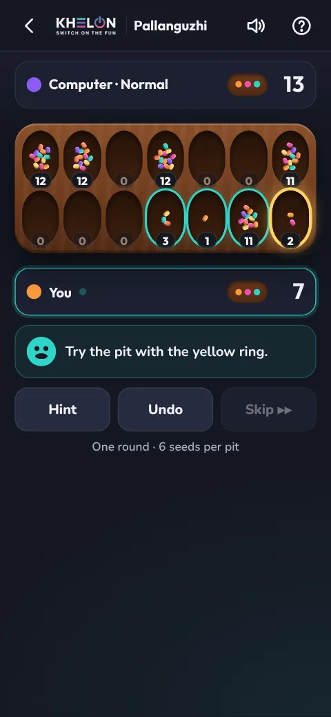 A Pallanguzhi game in progress, with a yellow ring on the pit the Hint suggests